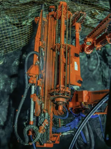 A bolter boom raised to meshed back underground.